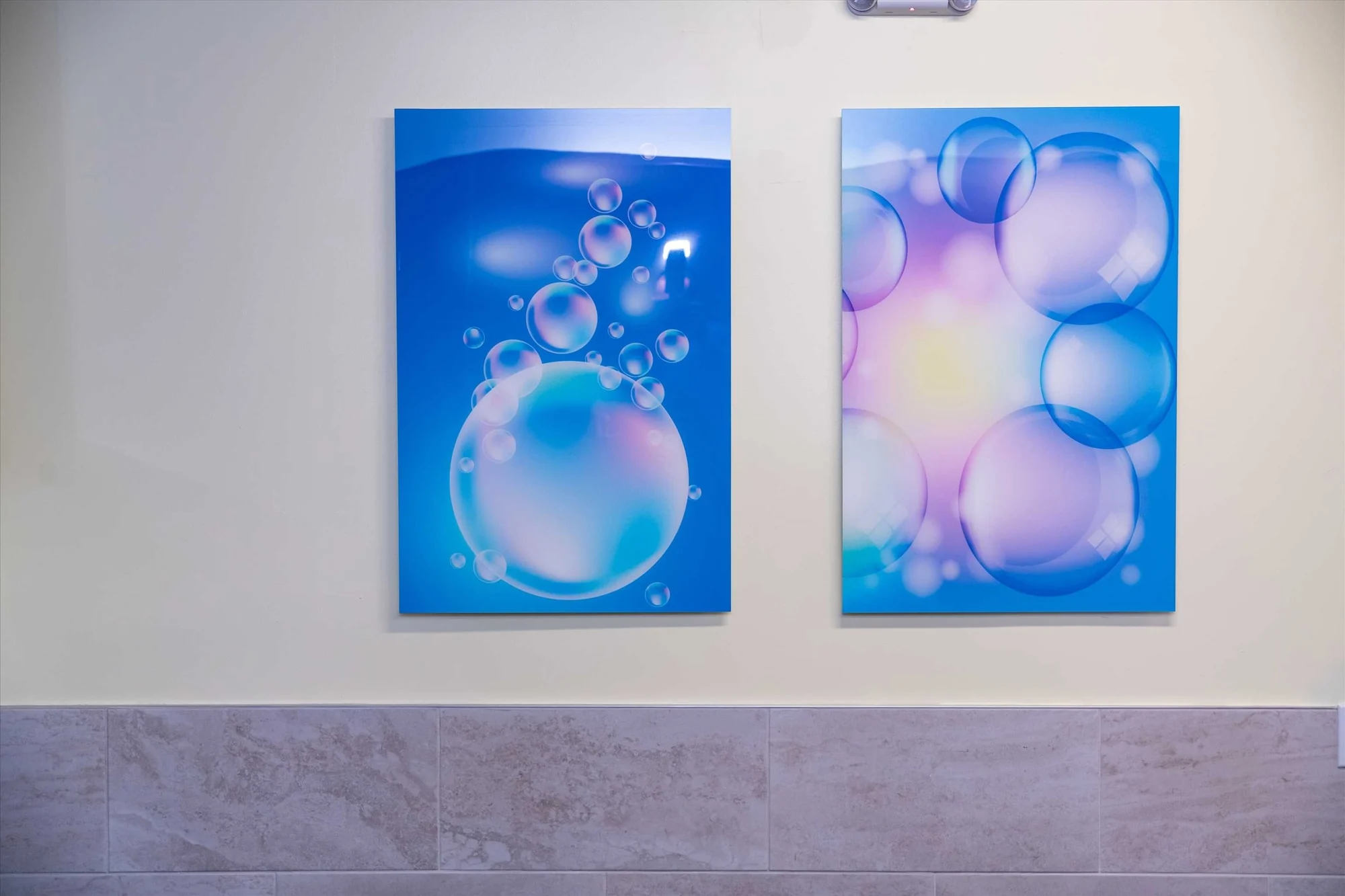 AC Pediatric Dentistry & Orthodontics — Detail of two blue bubble art panels above a stone-look tile wainscot