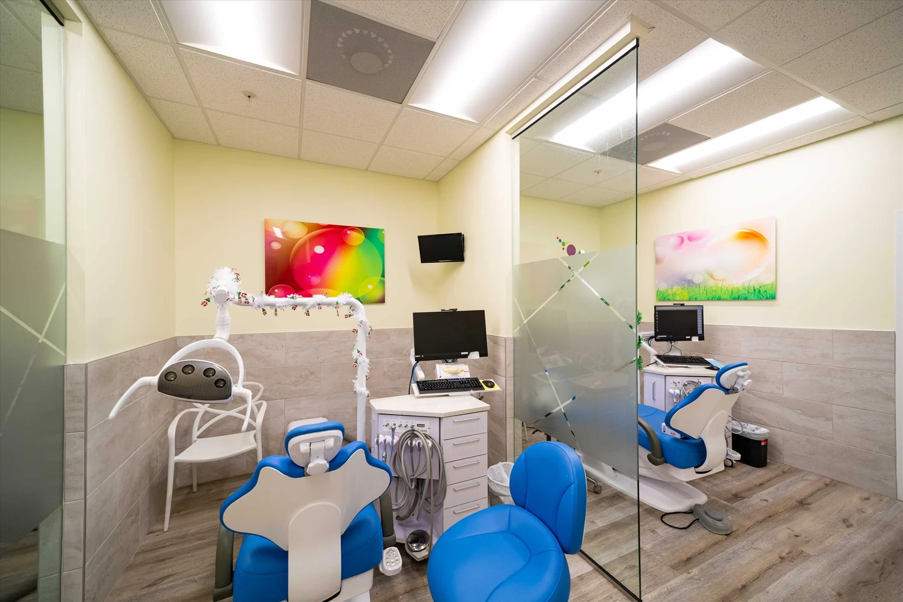 AC Pediatric Dentistry & Orthodontics — Two treatment bays with blue dental chairs and bubble art, separated by a partly frosted glass panel