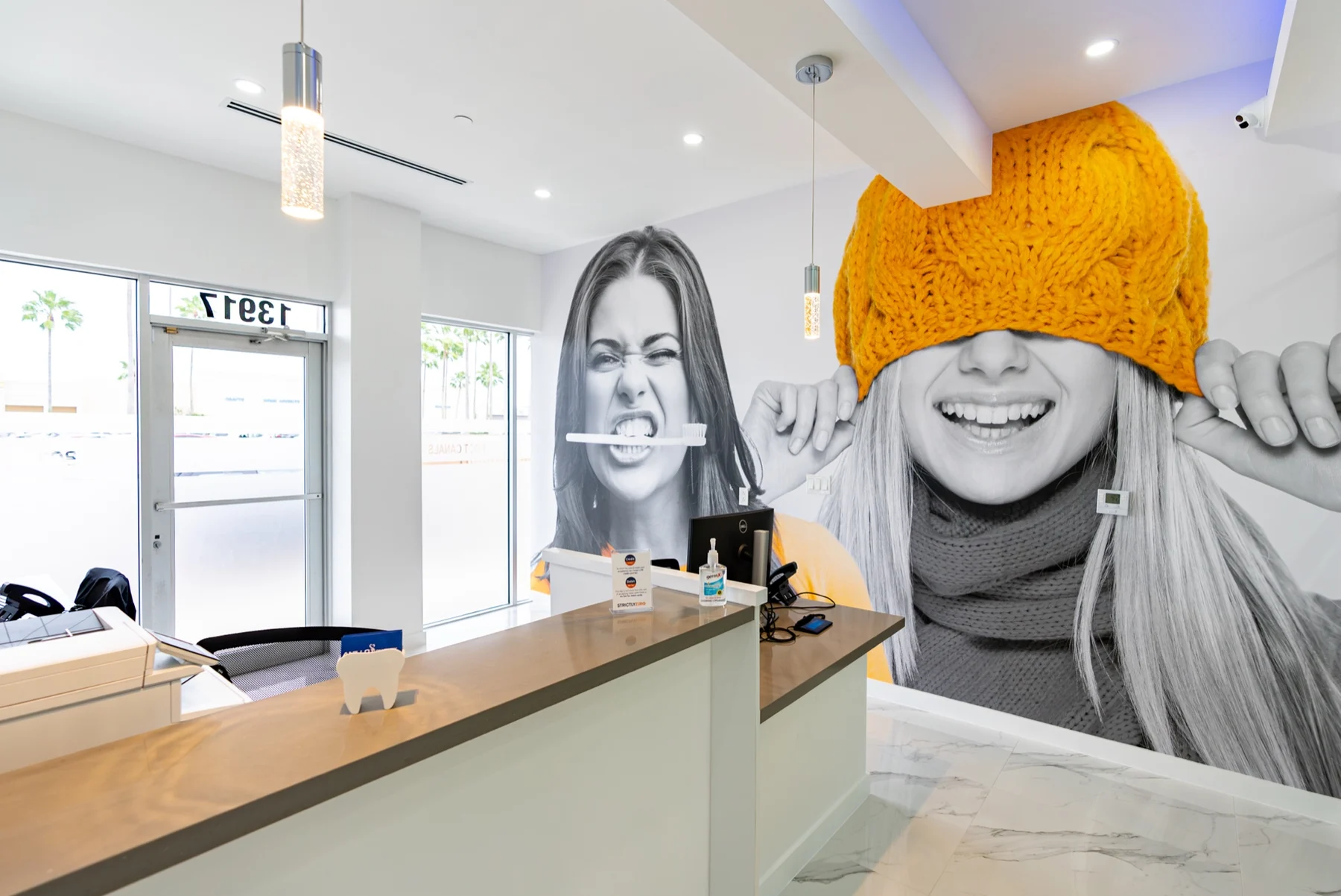 Anillo Dentistry — Mostrador de recepción frente a un mural en blanco y negro de dos caras, una bajo un gorro tejido amarillo