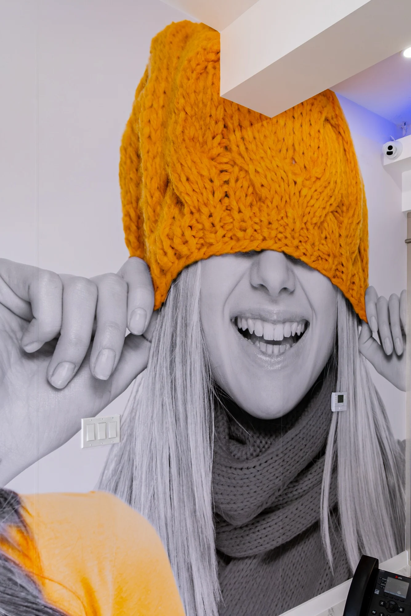 Anillo Dentistry — Detalle del mural: una cara que ríe bajo un gorro tejido amarillo que le tapa los ojos