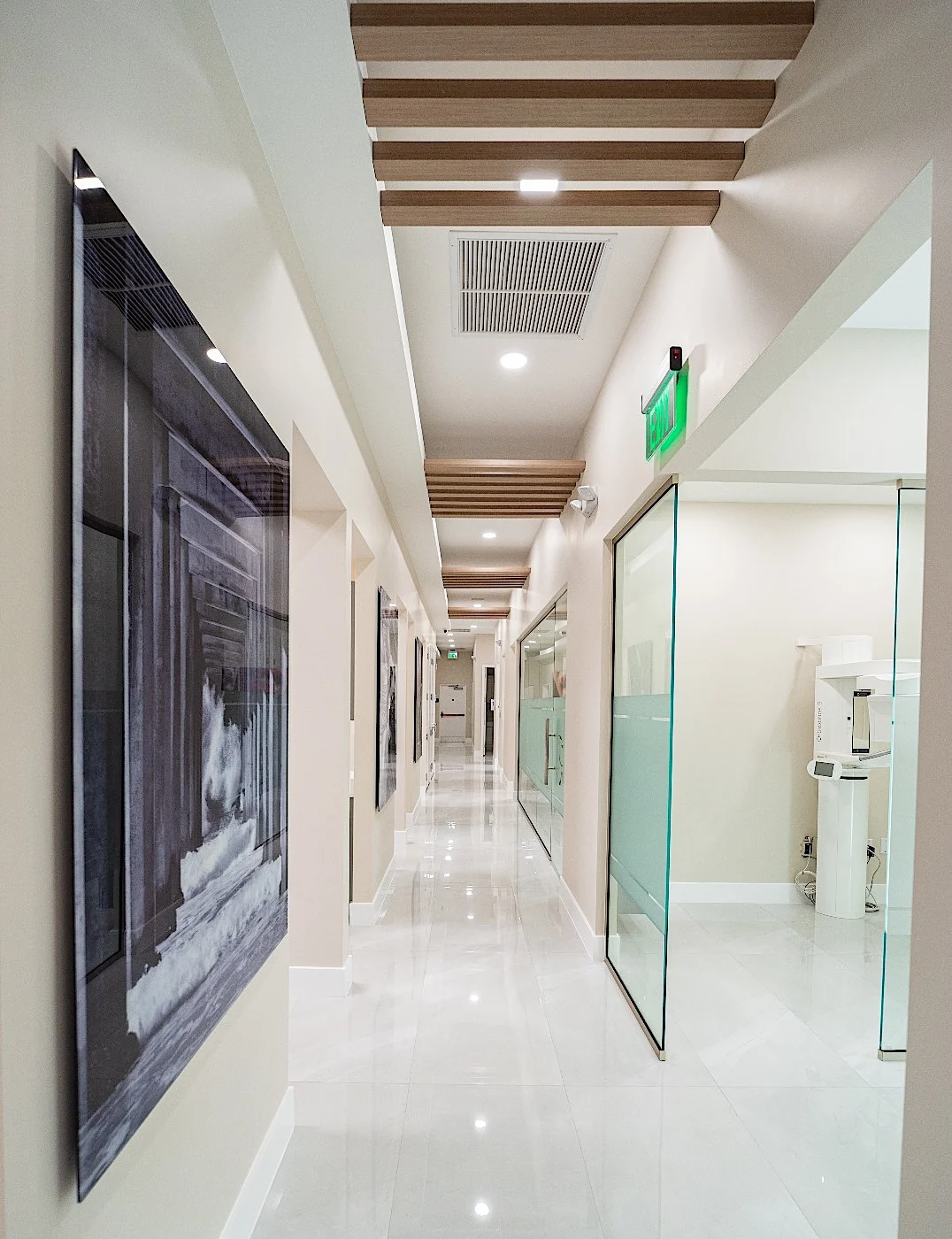 Clear Smiles Dental — Pasillo largo con un panel en blanco y negro, mamparas de vidrio y vigas de madera en el techo