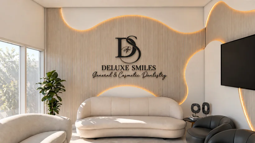 Deluxe Smiles — Waiting area with a curved cream sofa below the “DELUXE SMILES” logo on a backlit wavy slat wall