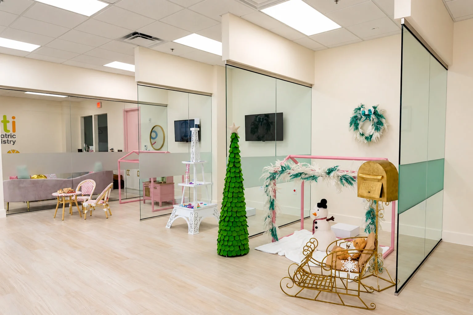Denti Pediatric Dentistry — Play area with glass partitions, a gold sleigh and holiday decorations beside a pink house frame