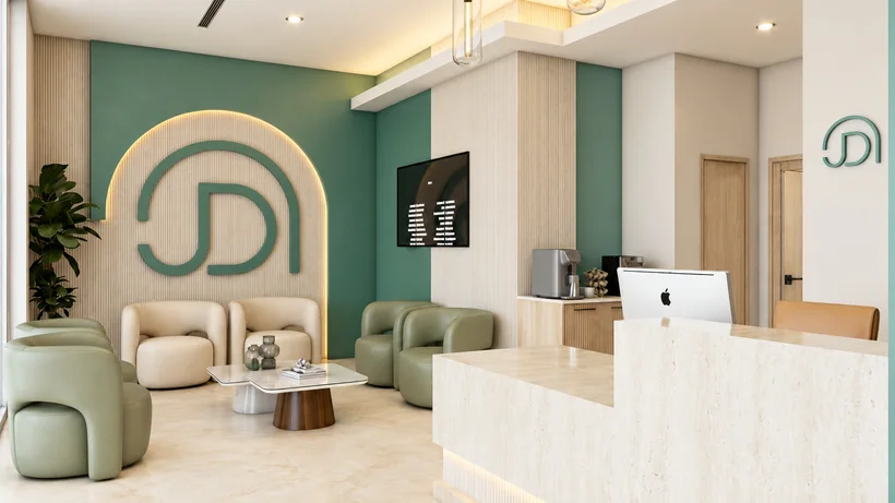 June Dental — Waiting area with its arched, backlit monogram wall, seen at an angle beside the stone-look reception desk