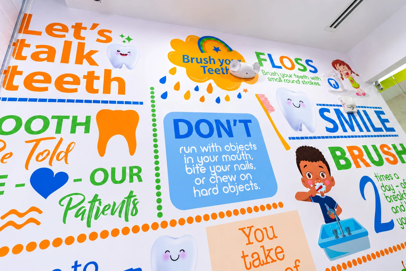 Little Sparkle Pediatric Dentistry — Full-height mural of dental advice in bold lettering — brush, floss, smile — with cartoon teeth and children