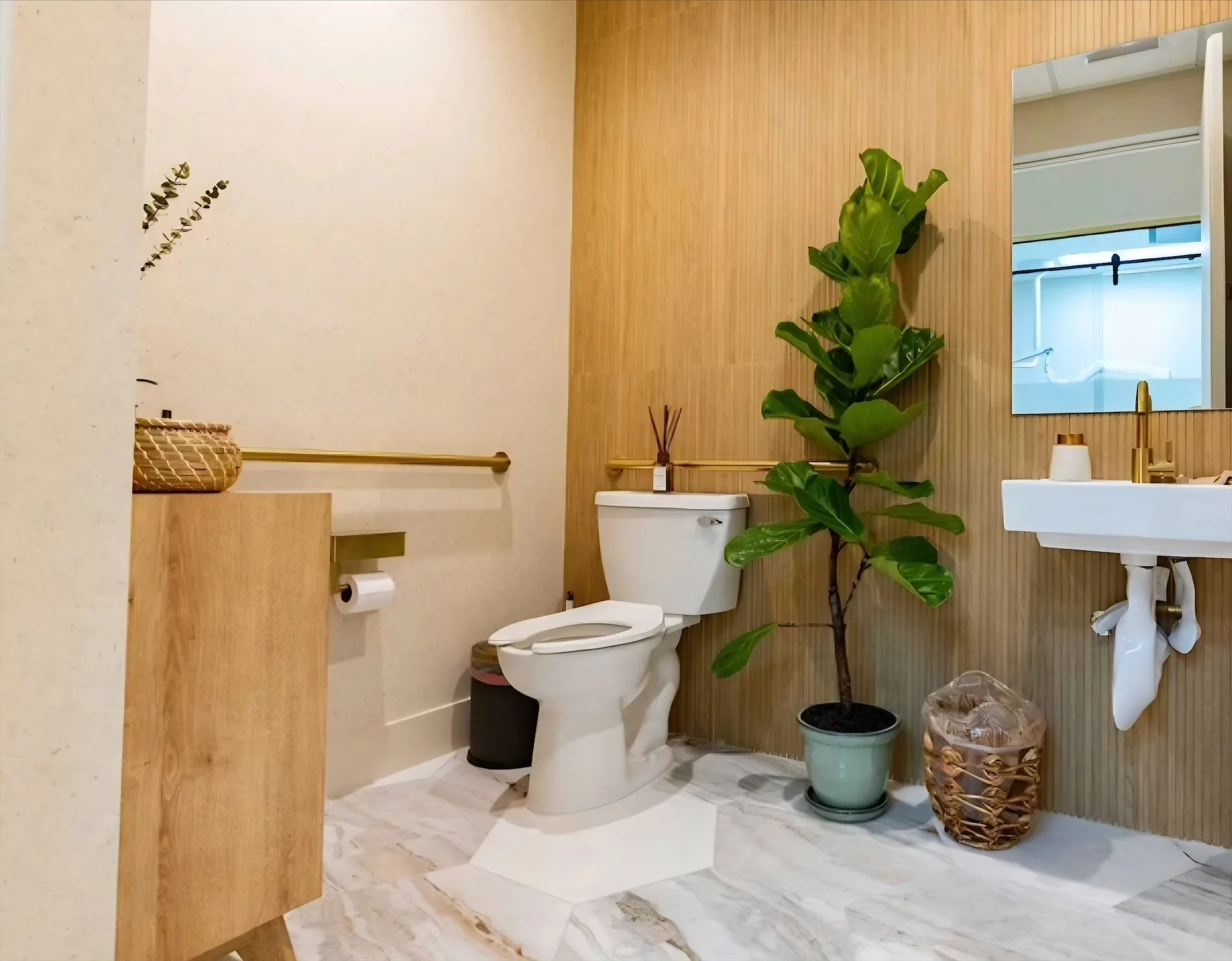 Nutridentist — Baño con pared de textura de madera, lavamanos suspendido con grifo dorado y una higuera en maceta