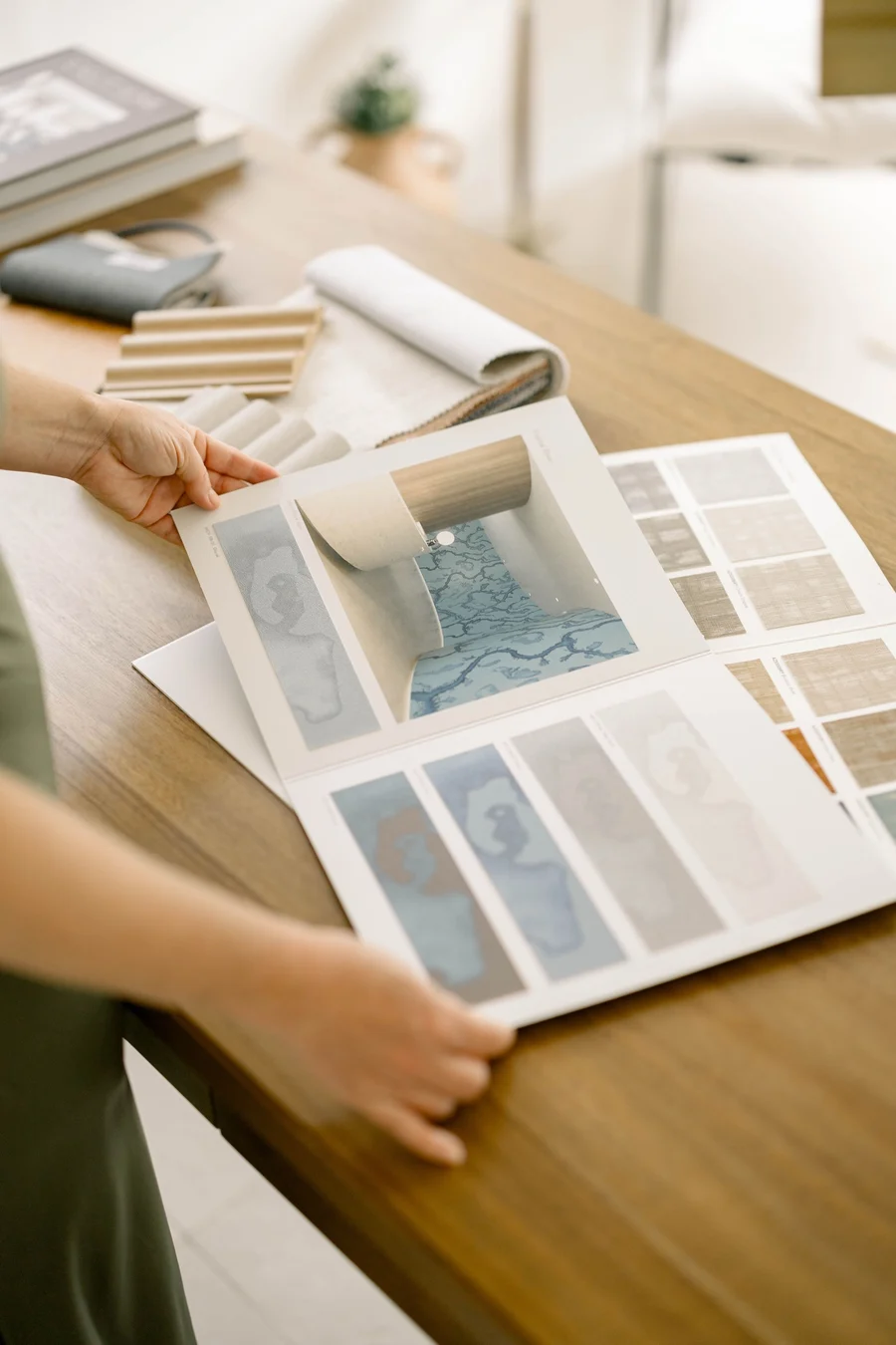 Hands laying out colour and material boards on a wooden desk
