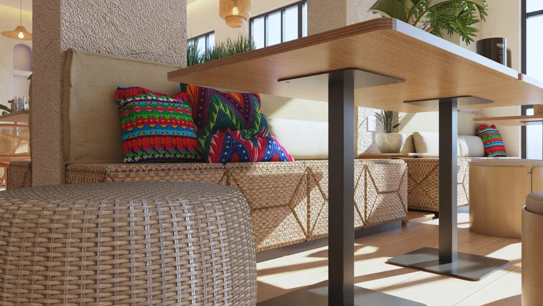 Restaurants — Close-up of a woven banquette with brightly patterned cushions beside a wood table on a black base