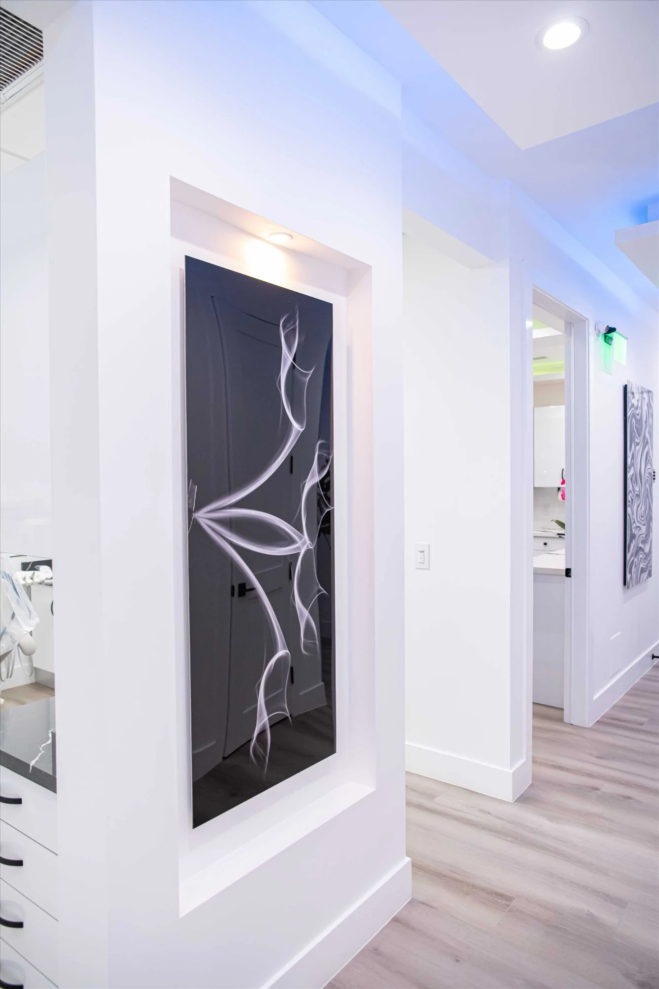 Select Dental Care — Panel negro con un dibujo de líneas blancas dentro de un nicho iluminado del pasillo